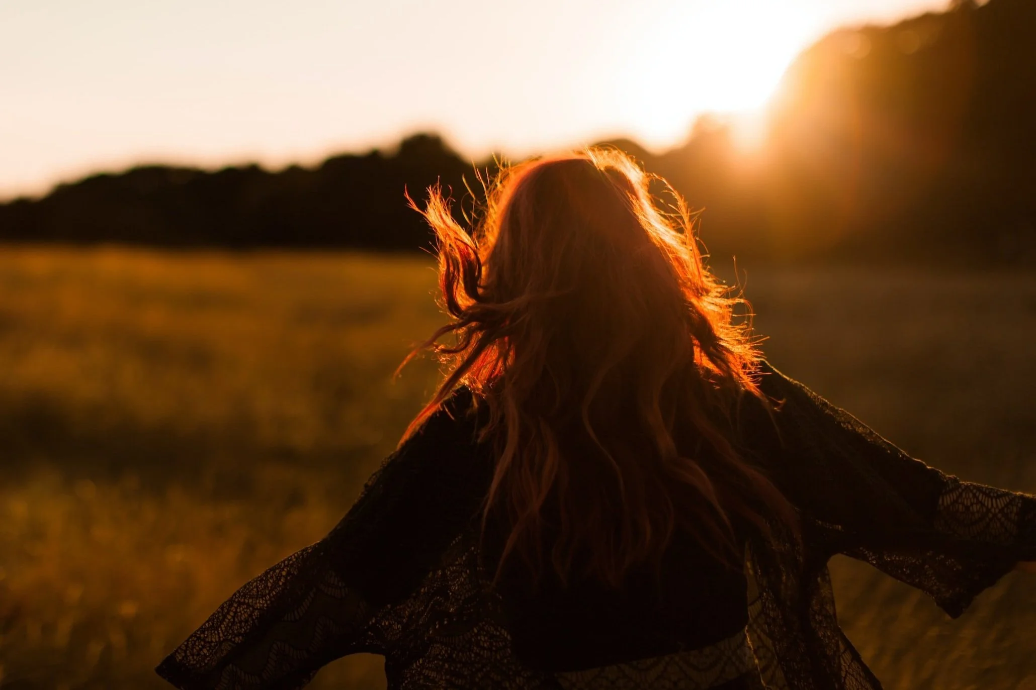 female presenting neurodivergent human facing a sunny sky symbolizing mental health and wellness
