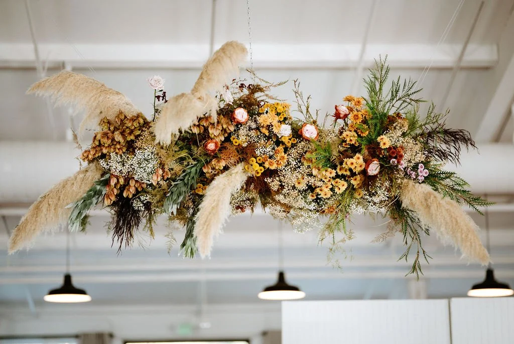 Arrangement of dried and fresh flowers with pampas grass hanging from the ceiling.