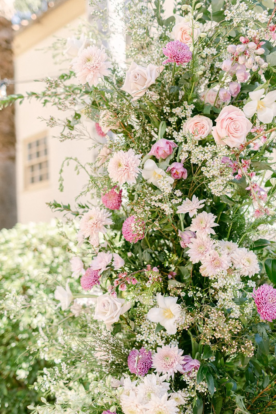 A tall bouquet of pink, white, and purple flowers including roses, dahlias, and other mixed blossoms with green foliage.