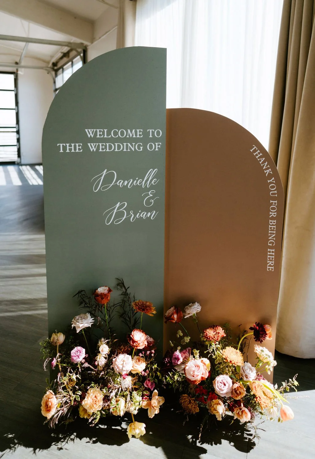 Wedding welcome sign with flowers, welcoming guests to Danielle and Brian's wedding, with a thank you message on the side.