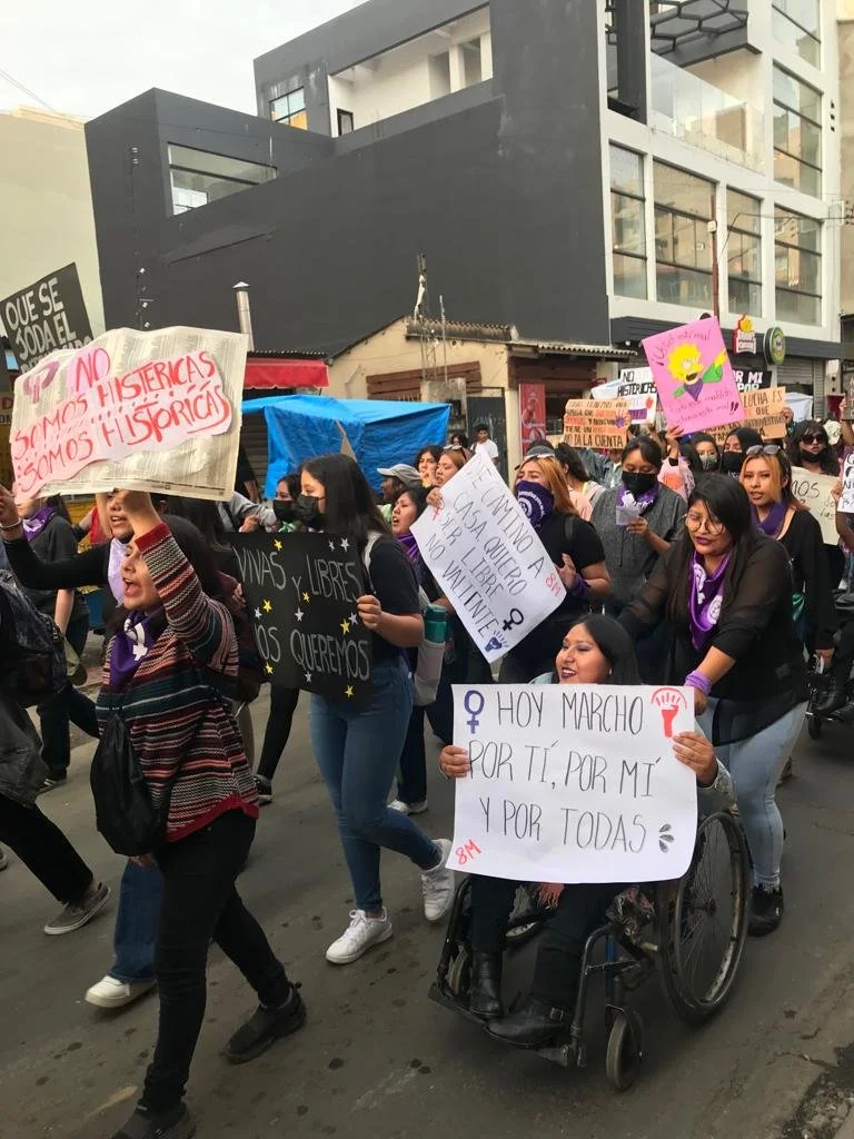 Mujeres diversas, incluyendo una mujer en sillas de ruedas, marchan en Cochabamba con carteles: "Hoy marcho por ti, por mí y por todas", "Vivas y libres nos queremos", "No somos histéricas, somos históricas".