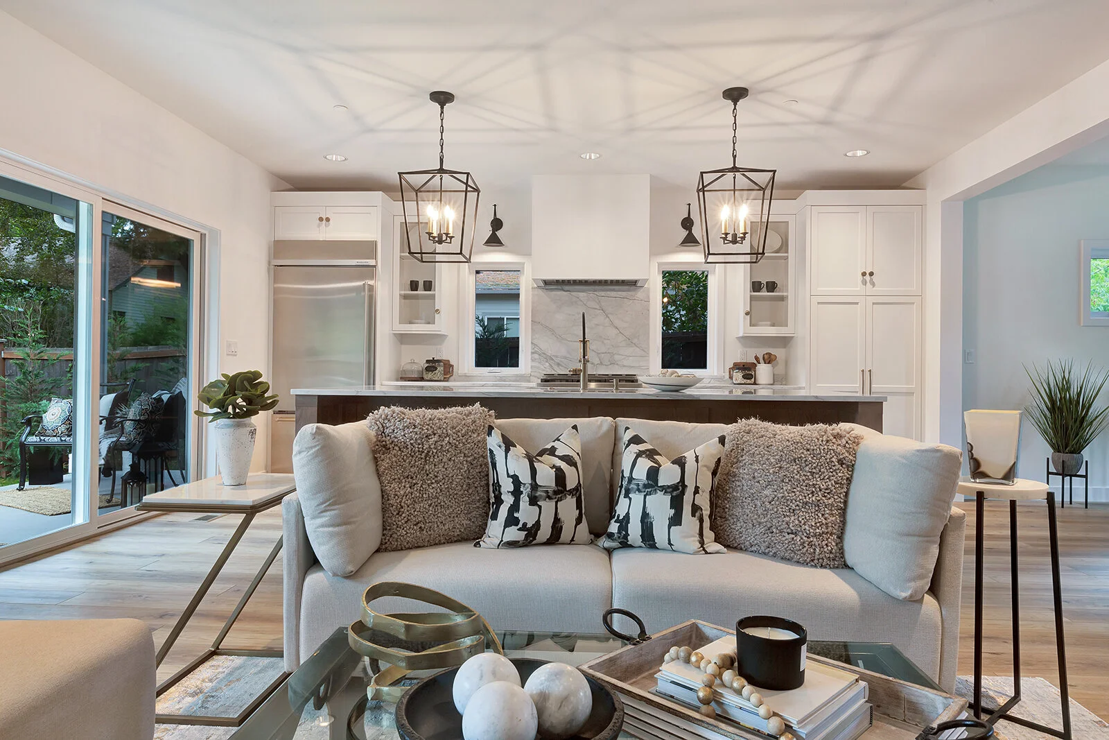 Open-concept living room and kitchen with white cabinetry, marble backsplash and pendant lights in a Seattle Eastside home