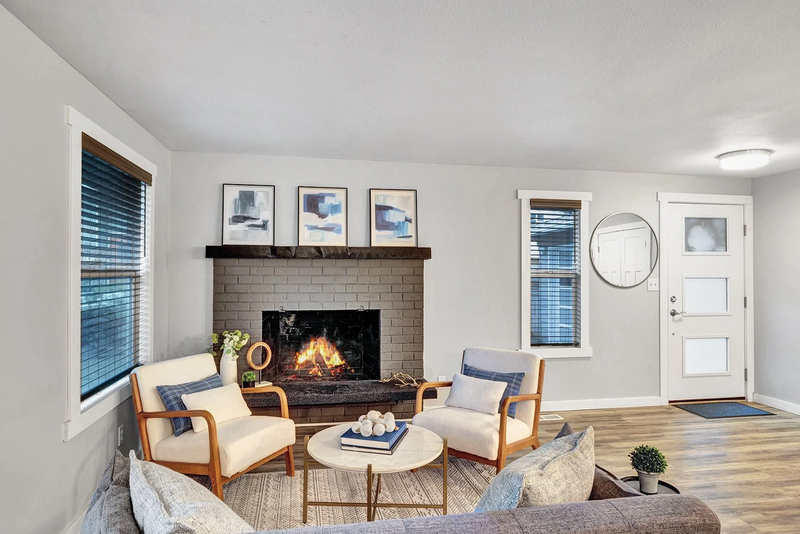 Open concept living room with fireplace in updated Kenmore rambler home showcasing modern design vinyl plank flooring and abundant natural light