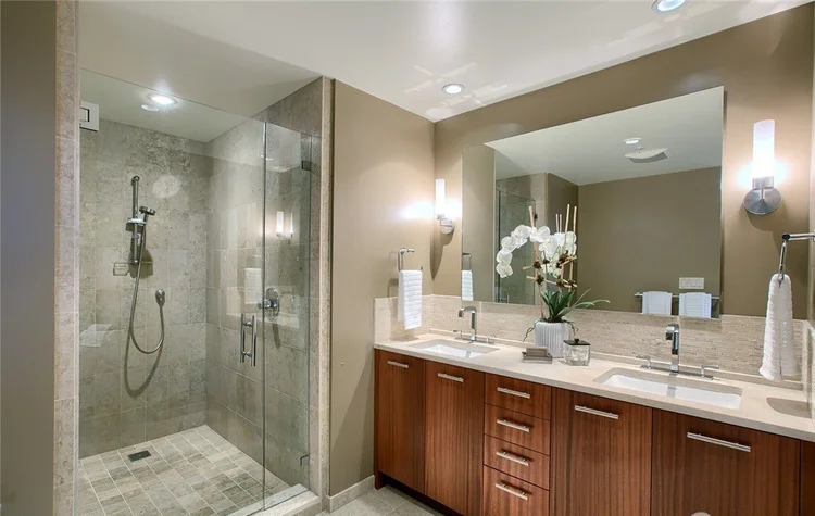 Spa-style primary bathroom with double vanity and glass walk-in shower at Bellevue Towers