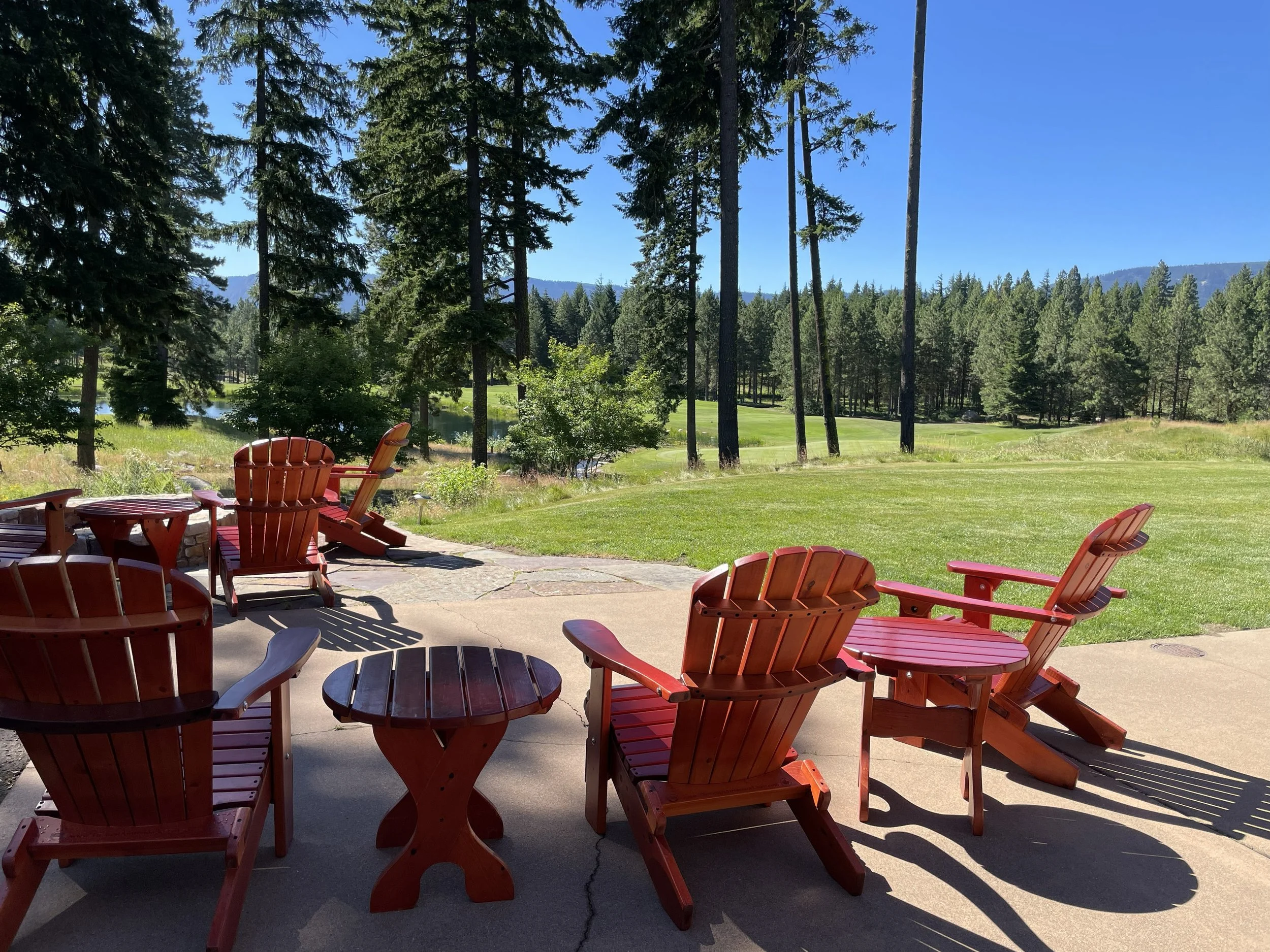 Red Adirondack chairs overlooking ponderosa pine forest and Cascade sky at Suncadia Resort, Cle Elum Washington — the four-season outdoor lifestyle