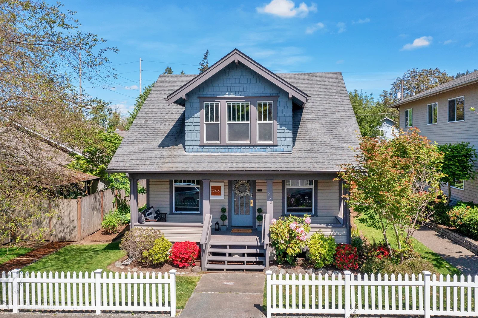 1920s Craftsman home at 250 SE Andrews Street in Downtown Issaquah with blue siding, white trim, gabled roofline, front porch, and manicured gardens