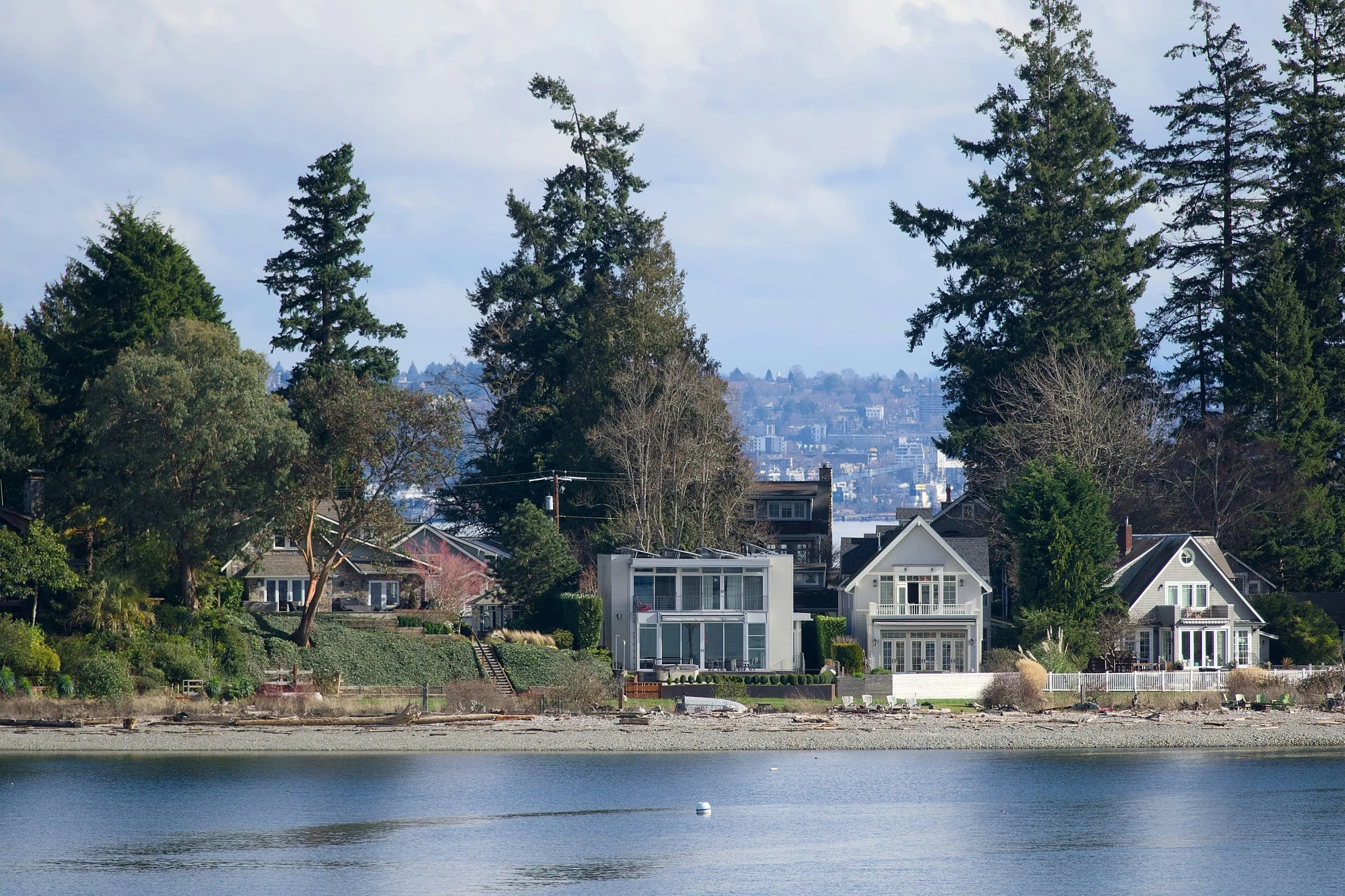 Older traditional home beside modern rebuilt waterfront home, Eastside shoreline setback regulations, Seattle skyline view