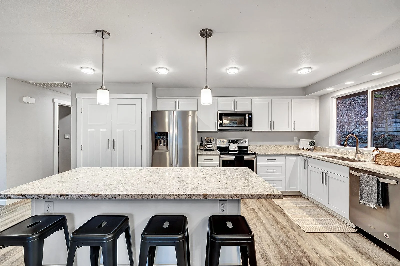 Remodeled gourmet kitchen in Finn Hill Kenmore home featuring white shaker cabinets quartz countertops stainless steel appliances and island seating for luxury entertaining