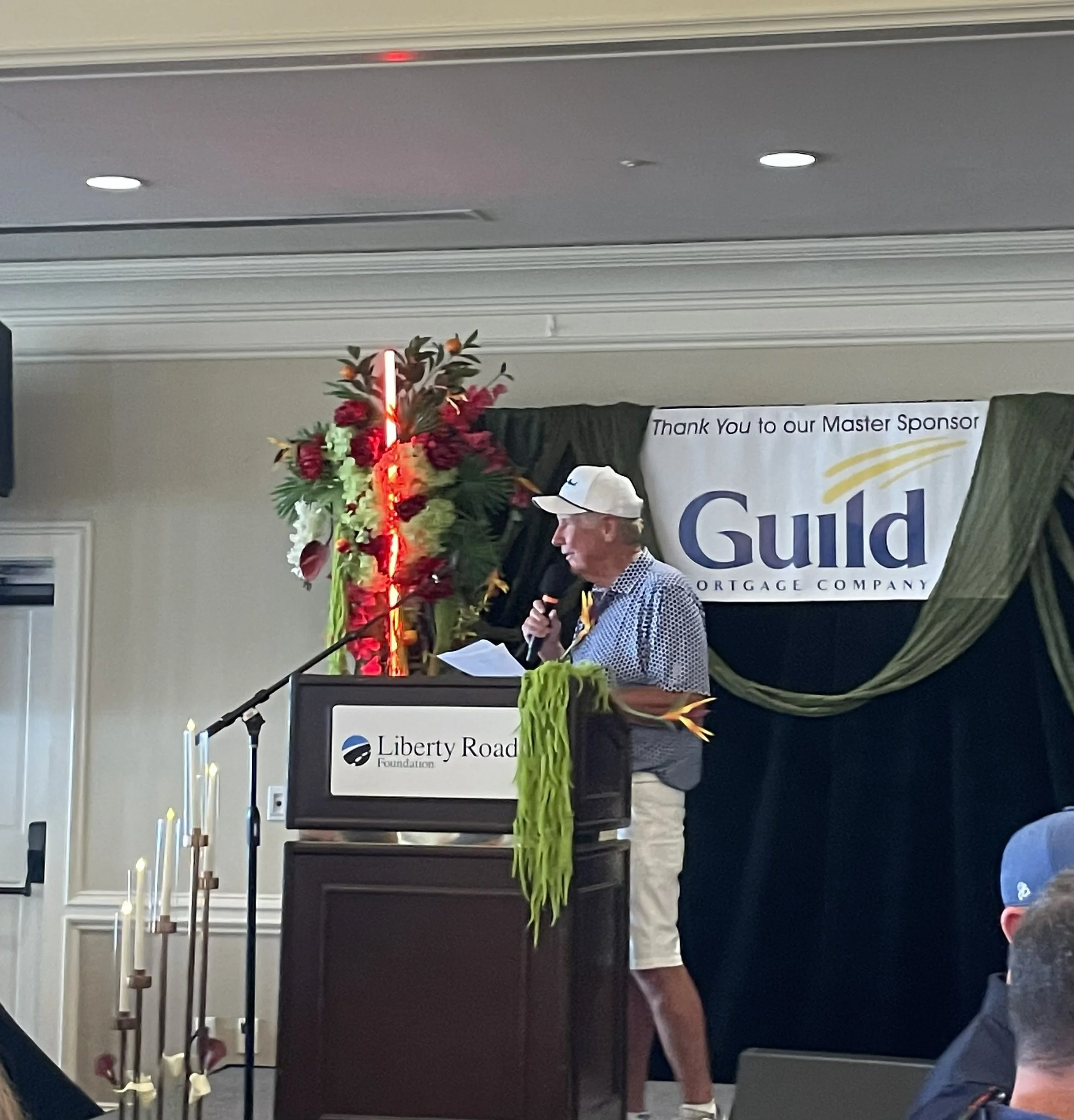 Liberty Road Foundation golf tournament emcee addressing guests, Guild Mortgage master sponsor