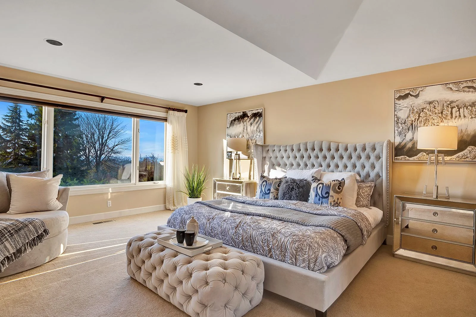 Luxury primary bedroom suite with tufted headboard, fireplace, and Lake Washington views in Clyde Hill home
