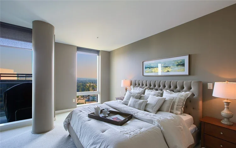 Primary bedroom with upholstered headboard and city-view window at Bellevue Towers