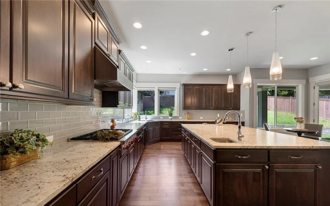 Luxury kitchen interior in a First Hill Mercer Island home featuring granite countertops, custom dark wood cabinetry, and hardwood floors