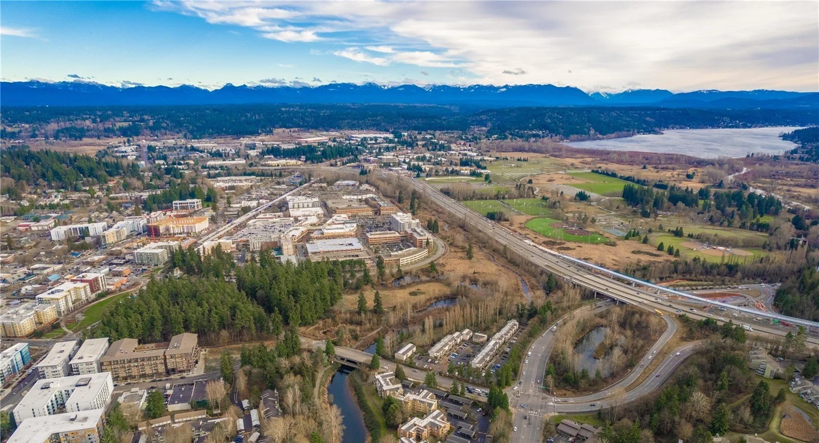 Aerial view of Downtown Redmond, Washington showing the light rail bridge, Cascade foothills, and Lake Sammamish