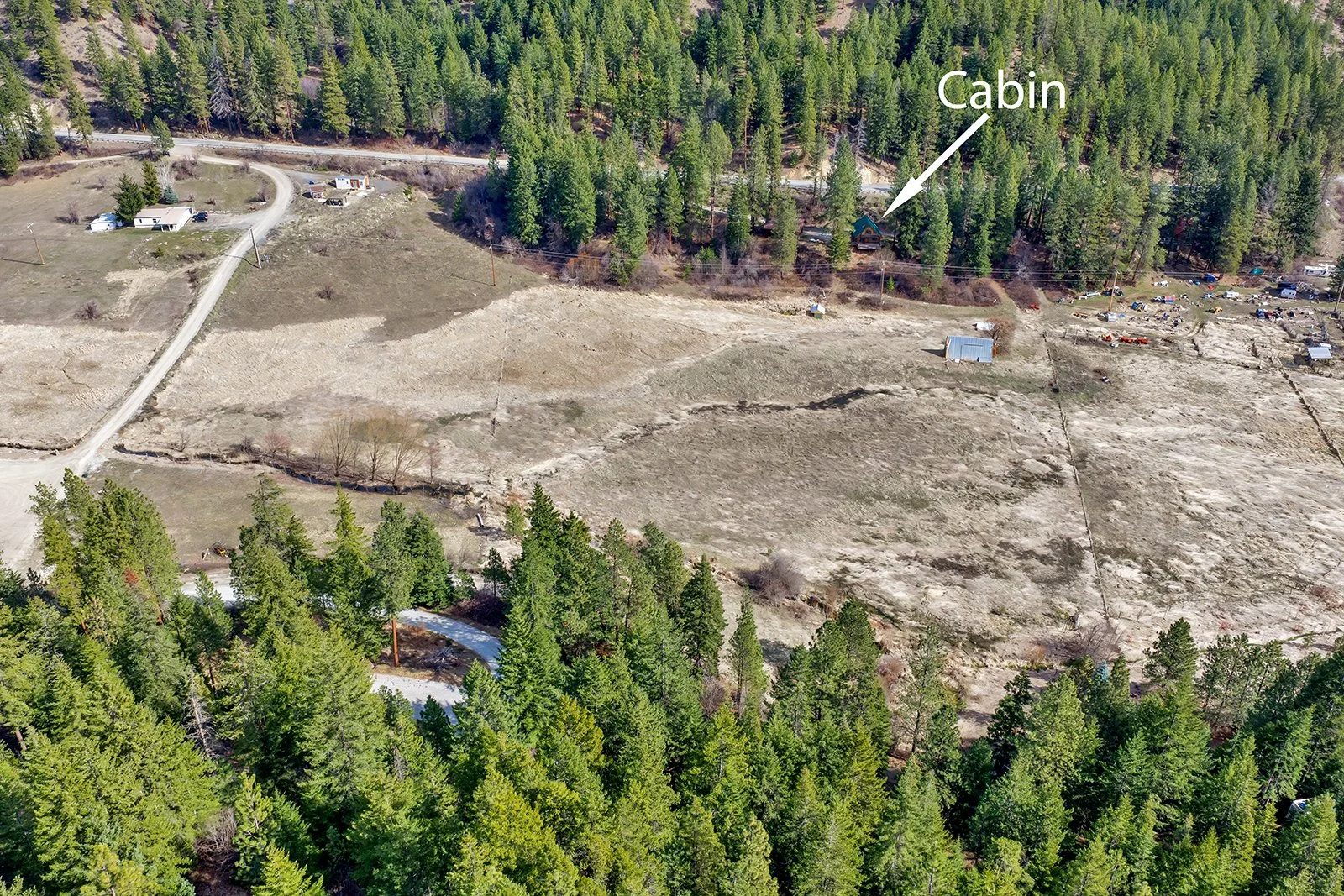 Aerial drone view of Pine Vista 17336 Chumstick Hwy showing 8.21 acres across two parcels in the Chumstick Valley Leavenworth Washington with pasture and creek