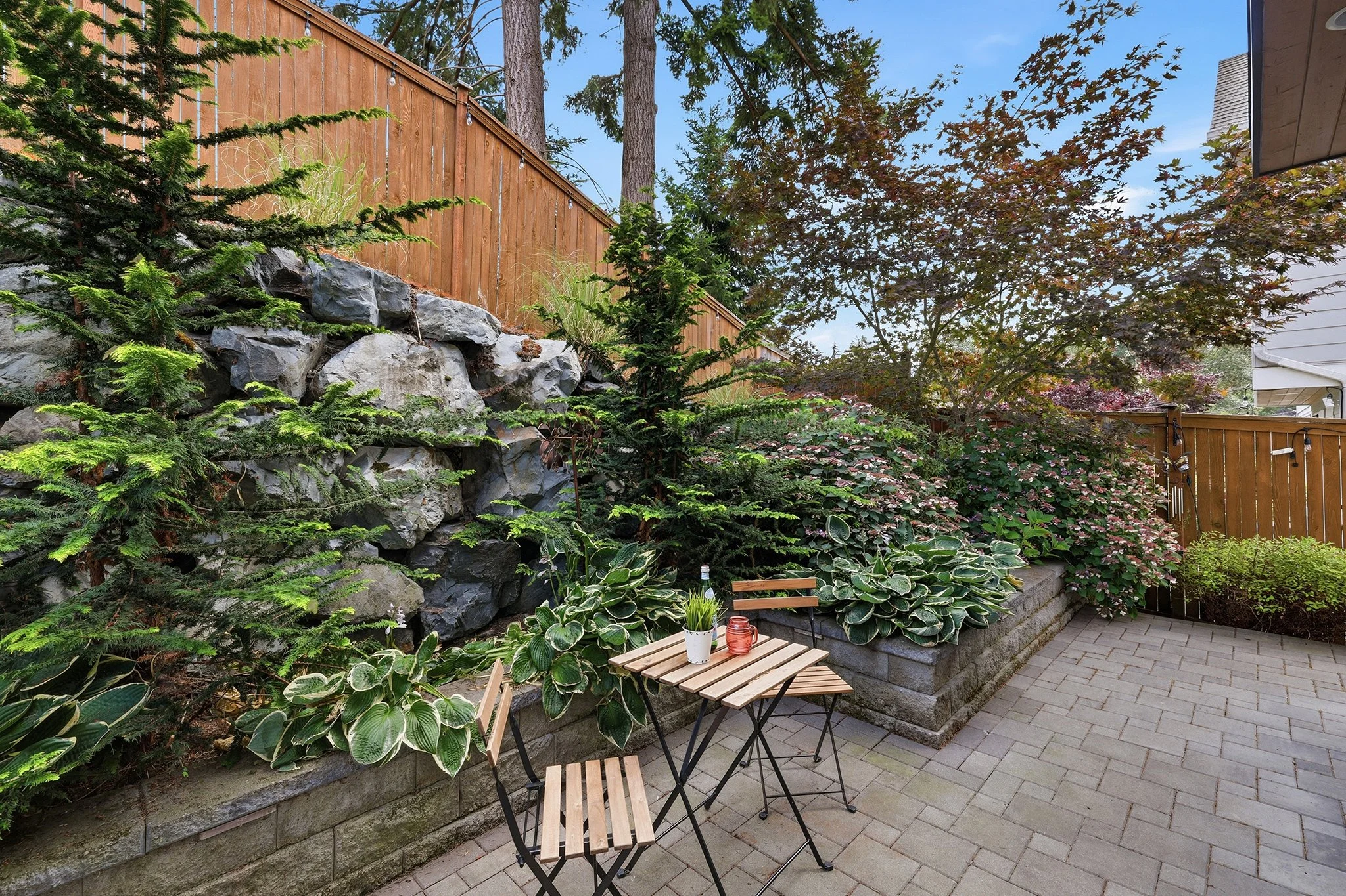 Backyard patio with stone retaining wall and paver seating area, English Hill Redmond luxury hom