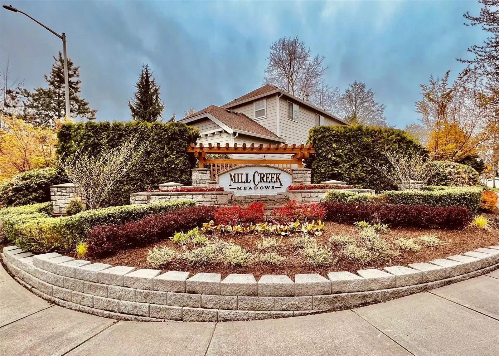Stone and wood entrance monument sign welcoming visitors to Mill Creek Meadows in Bothell, Washington