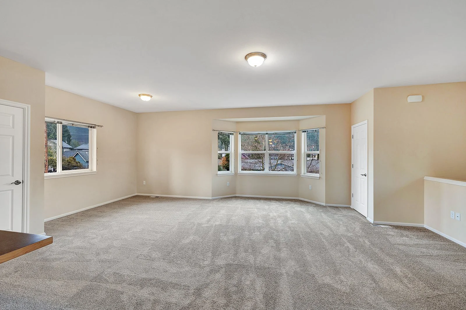 Bright open-concept living room with neutral finishes and natural light in lower unit of Old Town Issaquah duplex — 1,690 sq ft income unit at 260 SE Andrews Street featuring carpet and large windows