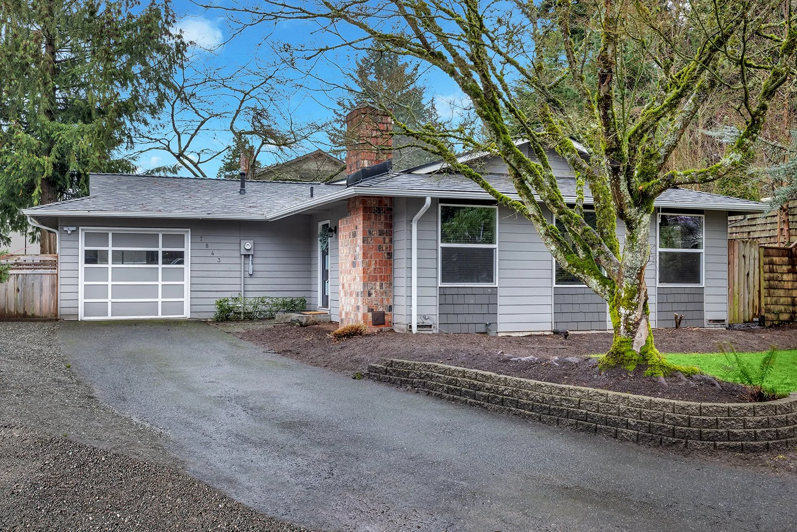 Curb appeal of updated Spanish rambler home at 7843 NE 146th Street in Finn Hill Kenmore Washington featuring mature trees and landscaped front yard