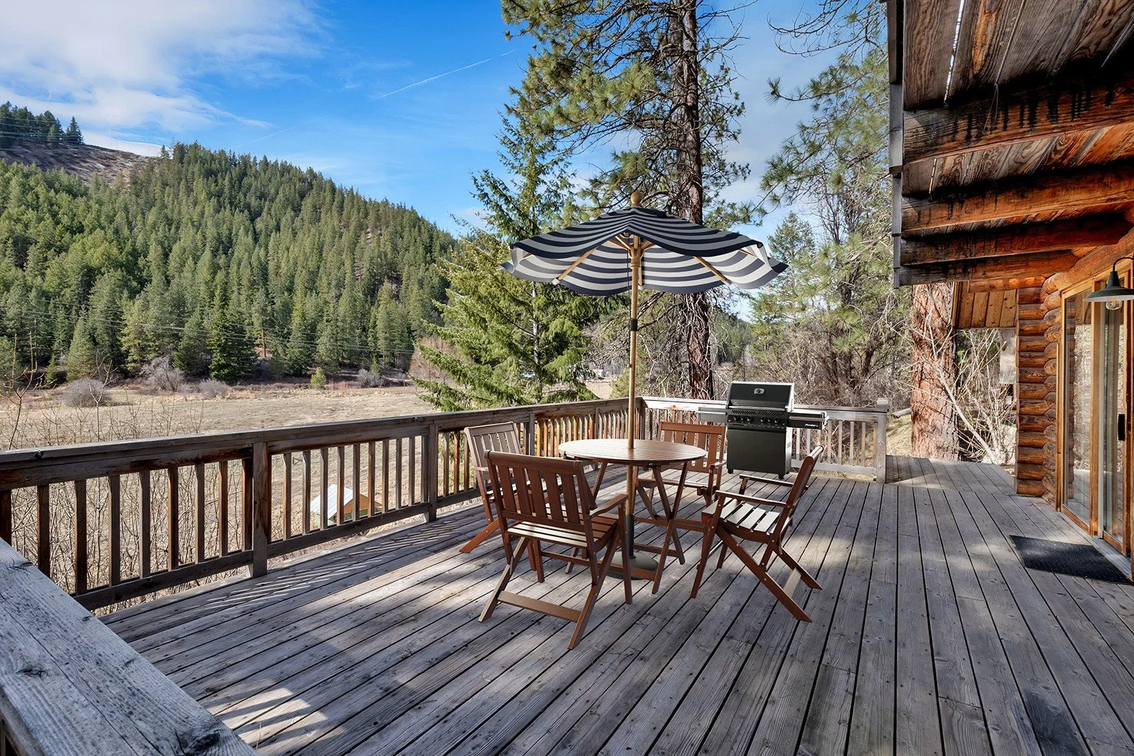 Large outdoor deck at Pine Vista log cabin 17336 Chumstick Hwy Leavenworth WA with creek frontage mountain views and al fresco dining space on 8 acres