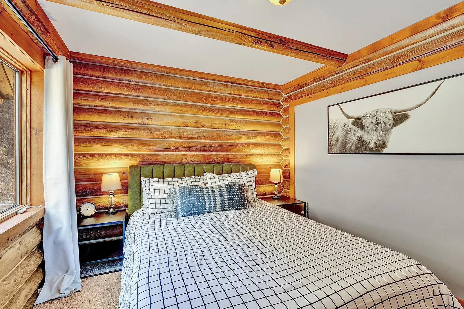 Main floor queen bedroom at Pine Vista log cabin Leavenworth WA with comfortable mountain lodge furnishings and log wall interior character