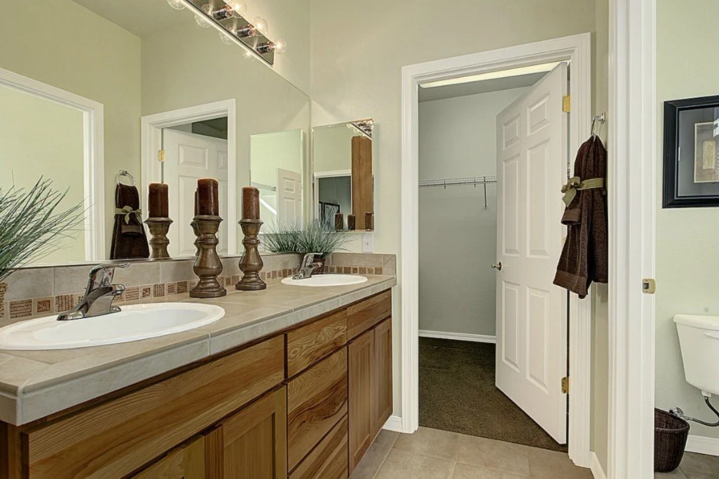 Primary bathroom with dual vanity and walk-in closet in Trilogy 55+ home