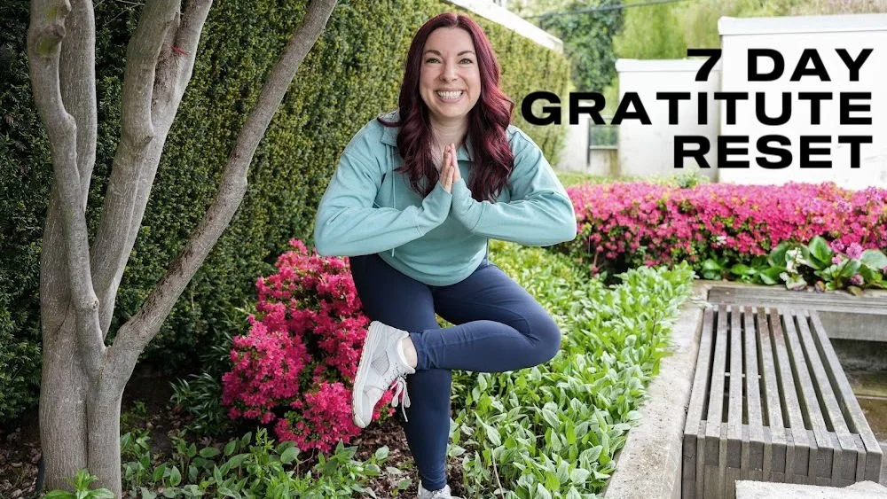 Title card for the 7 Day Gratitude Reset. Black text "7 Day Gratitude Reset" on a background of a woman doing a standing figure four yoga pose..