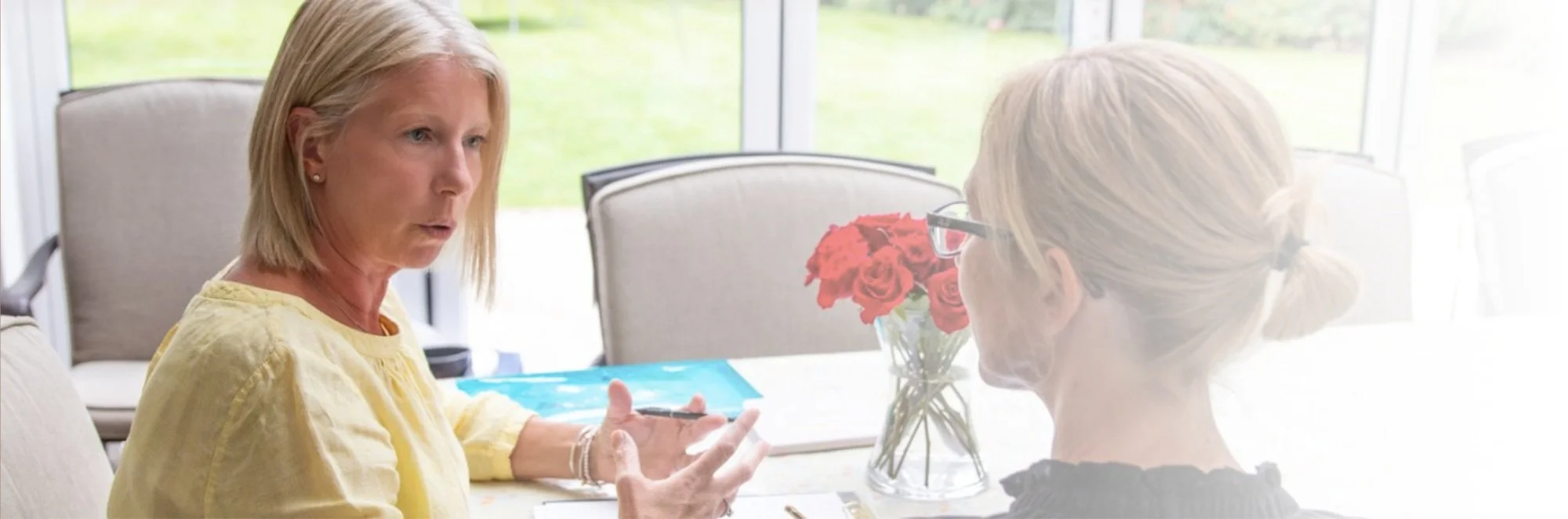 A career coach sitting at a table with a female client discussing career options