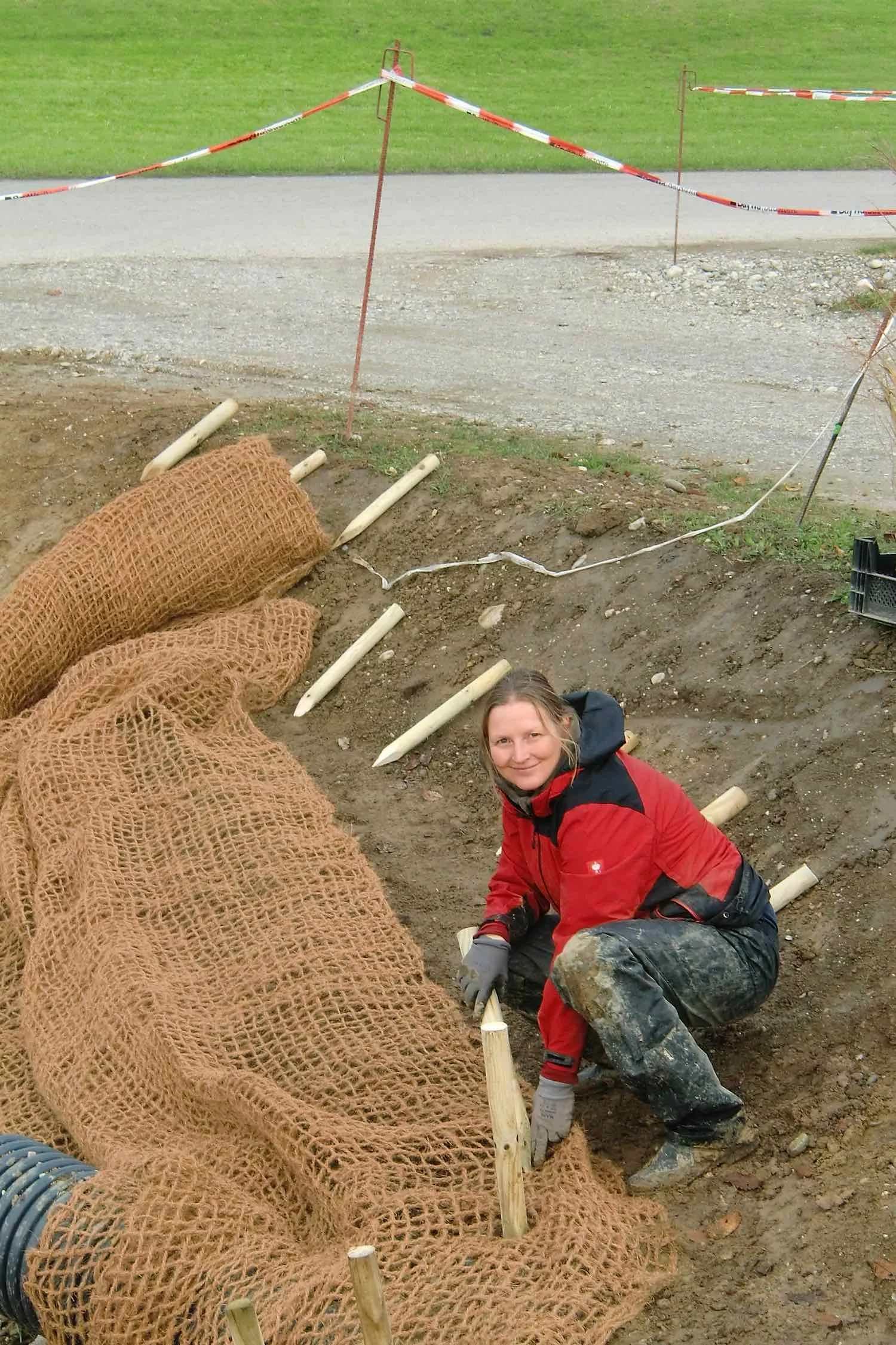 Susa befestigt Böschungsschutzmatten. So wird ein Abrutschen der Ränder verhindert, bis die Pflanzen für ausreichende Befestigung sorgen.