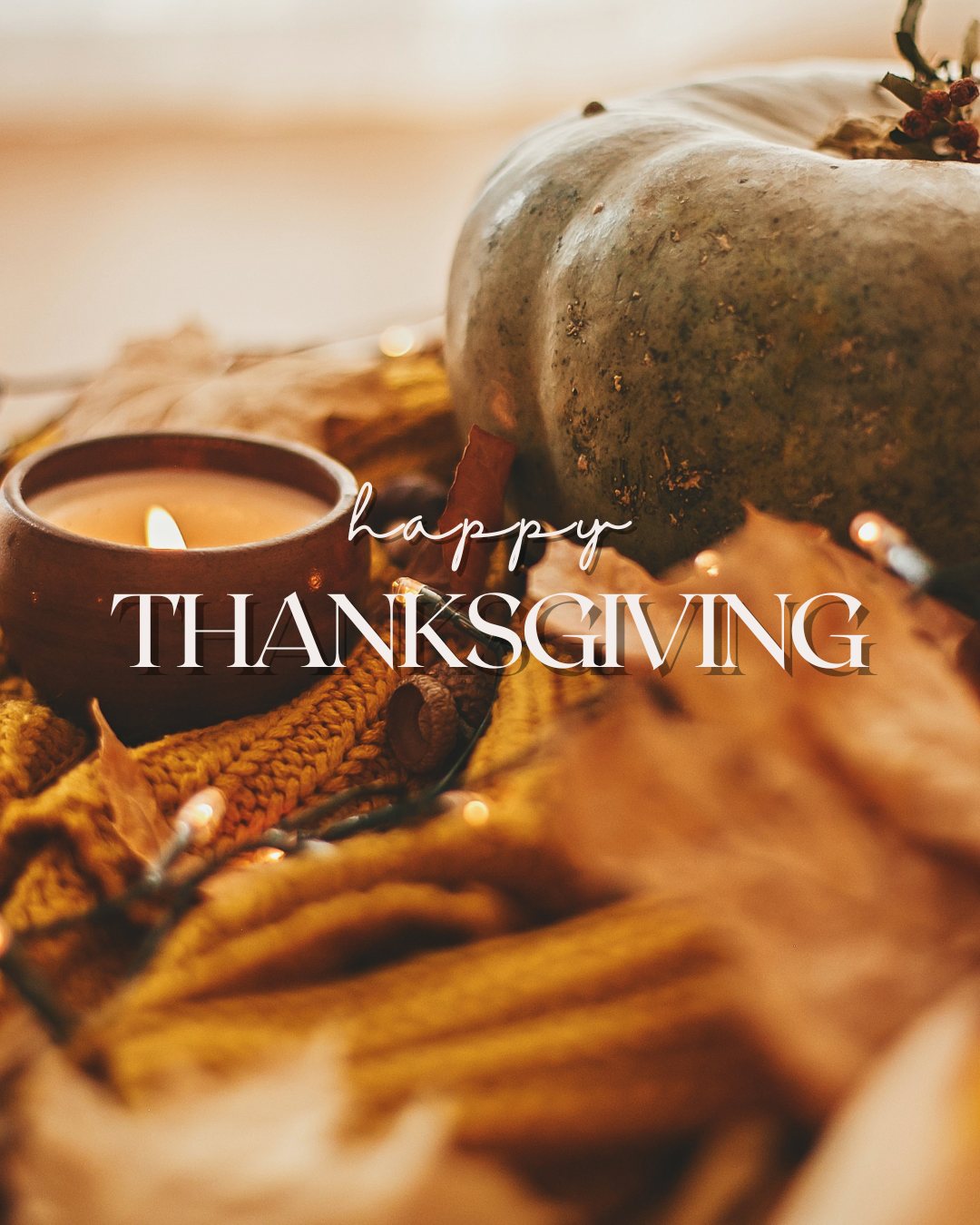 A pale green pumpkin beside a glowing candle, autumn leaves, and warm string lights, with the words “Happy Thanksgiving.”