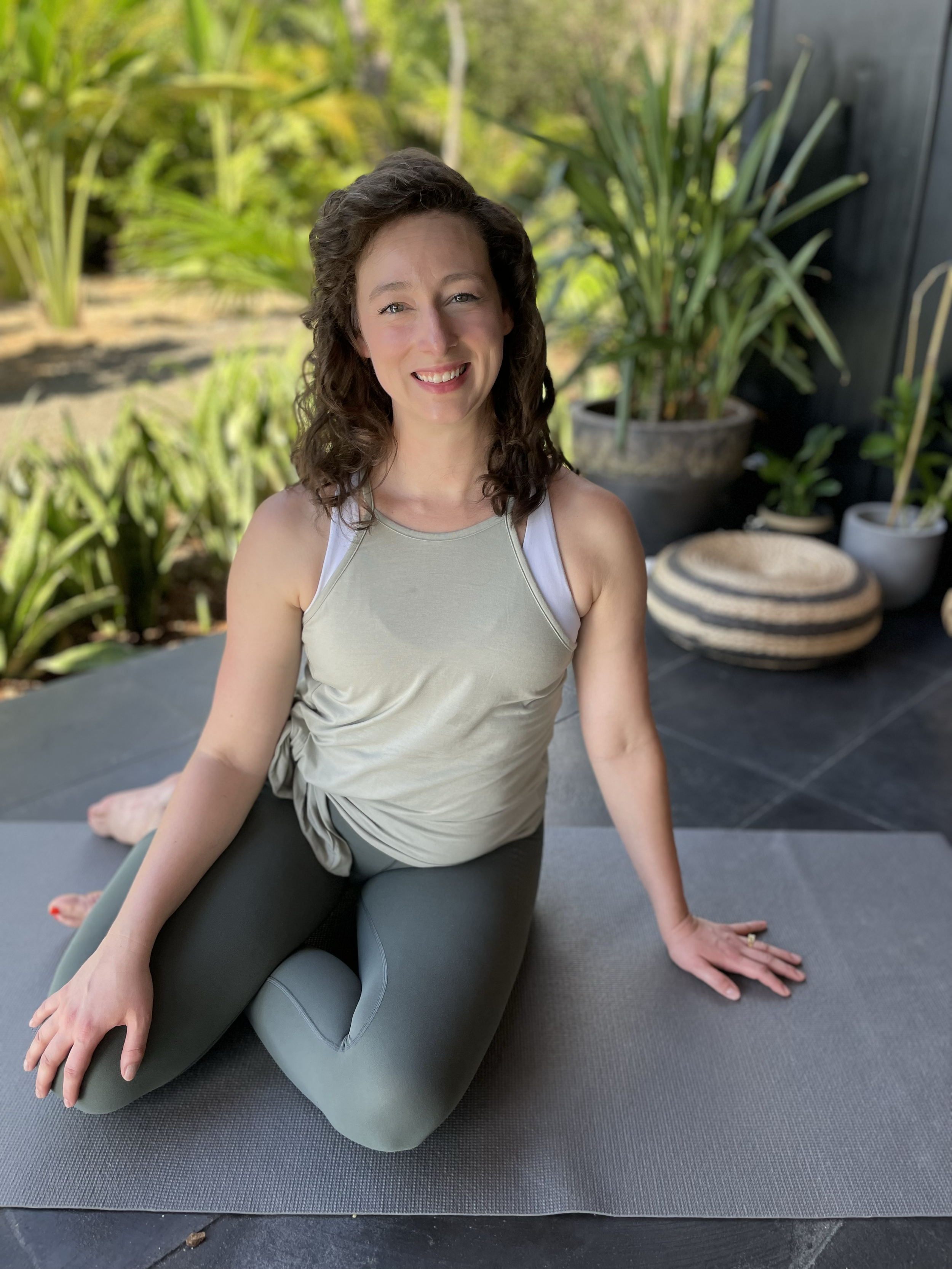 Brittany Dever, owner of Pathway Pilates Studio, seated on a mat outdoors.