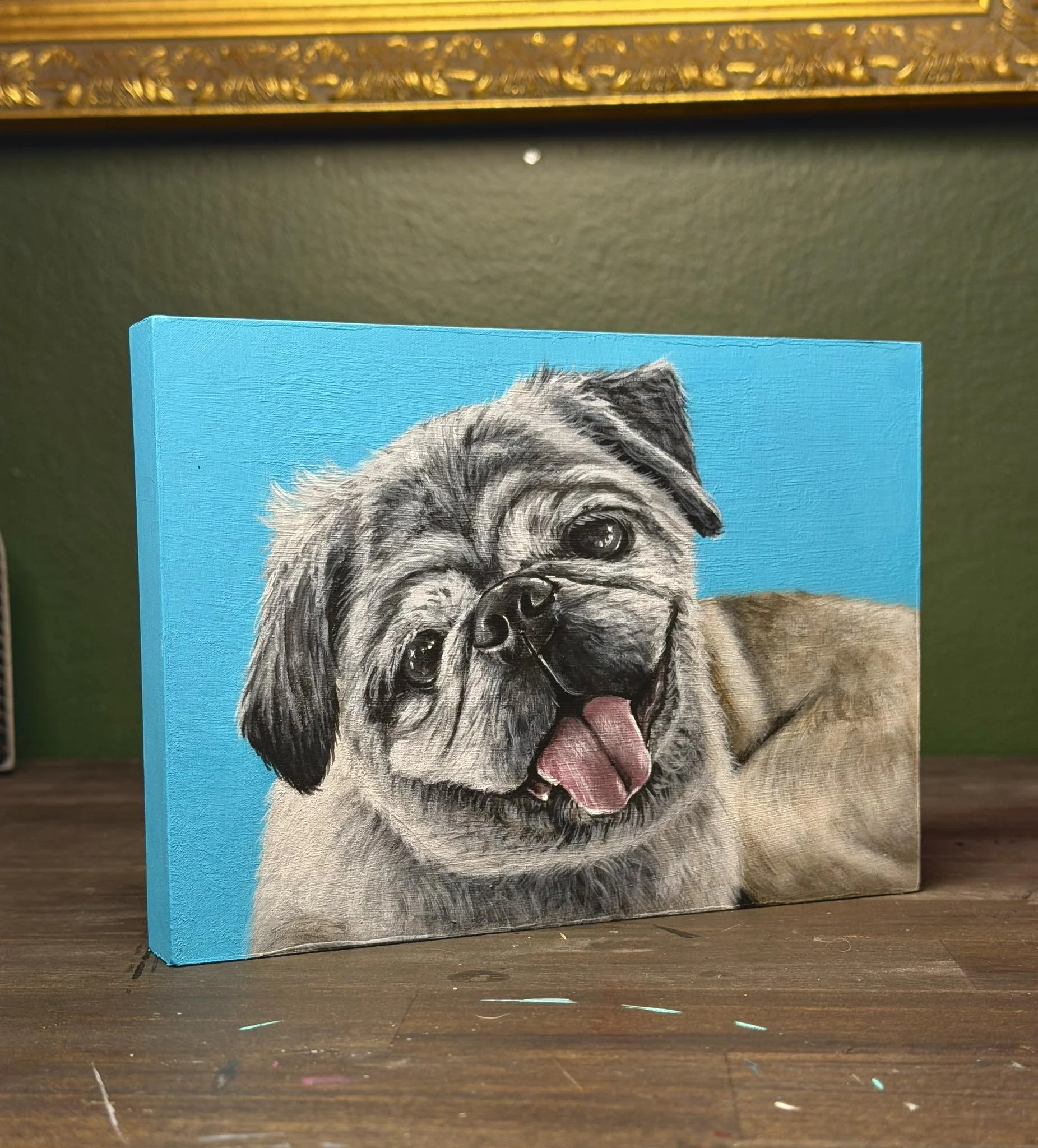 Painted canvas of a happy pug dog with its tongue out on a bright blue background.
