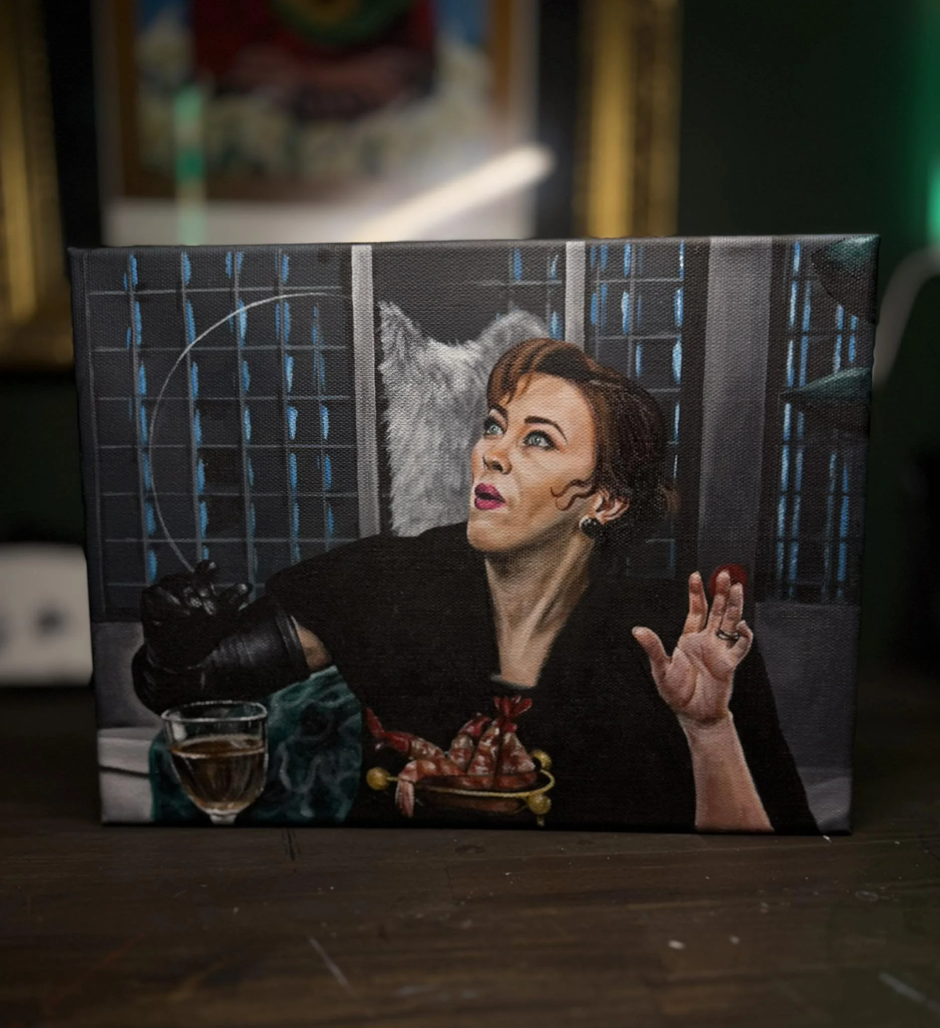 Painting of a woman with short brown hair and makeup, sitting at a table with a lobster and a glass of white wine, with a wolf behind her, in a cage-like background.