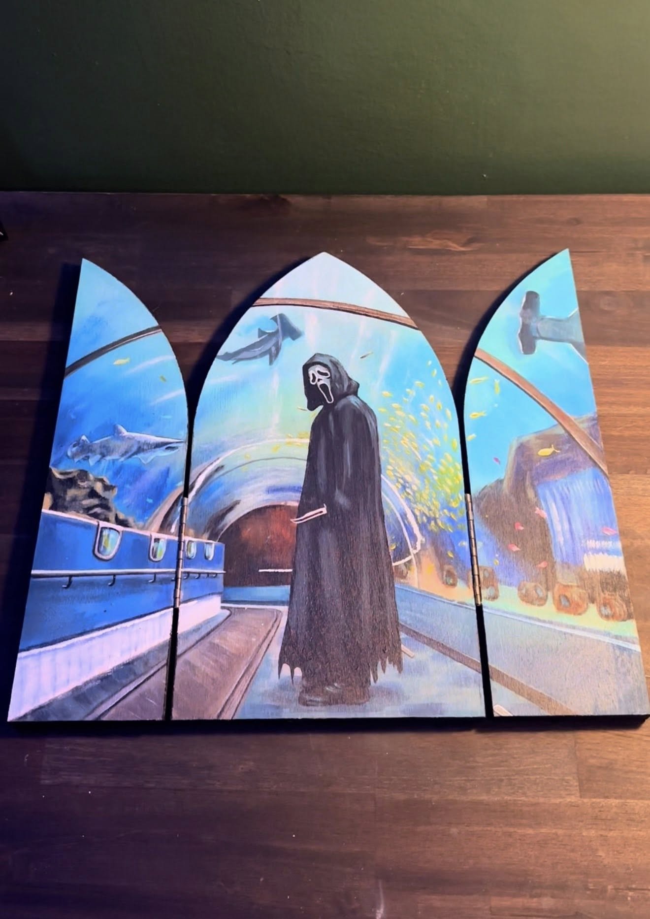 Painted triptych depicting a haunted subway scene with a ghostly figure in a dark coat and mask, surrounded by aquatic animals, underwater views, and a cityscape with waterfalls.