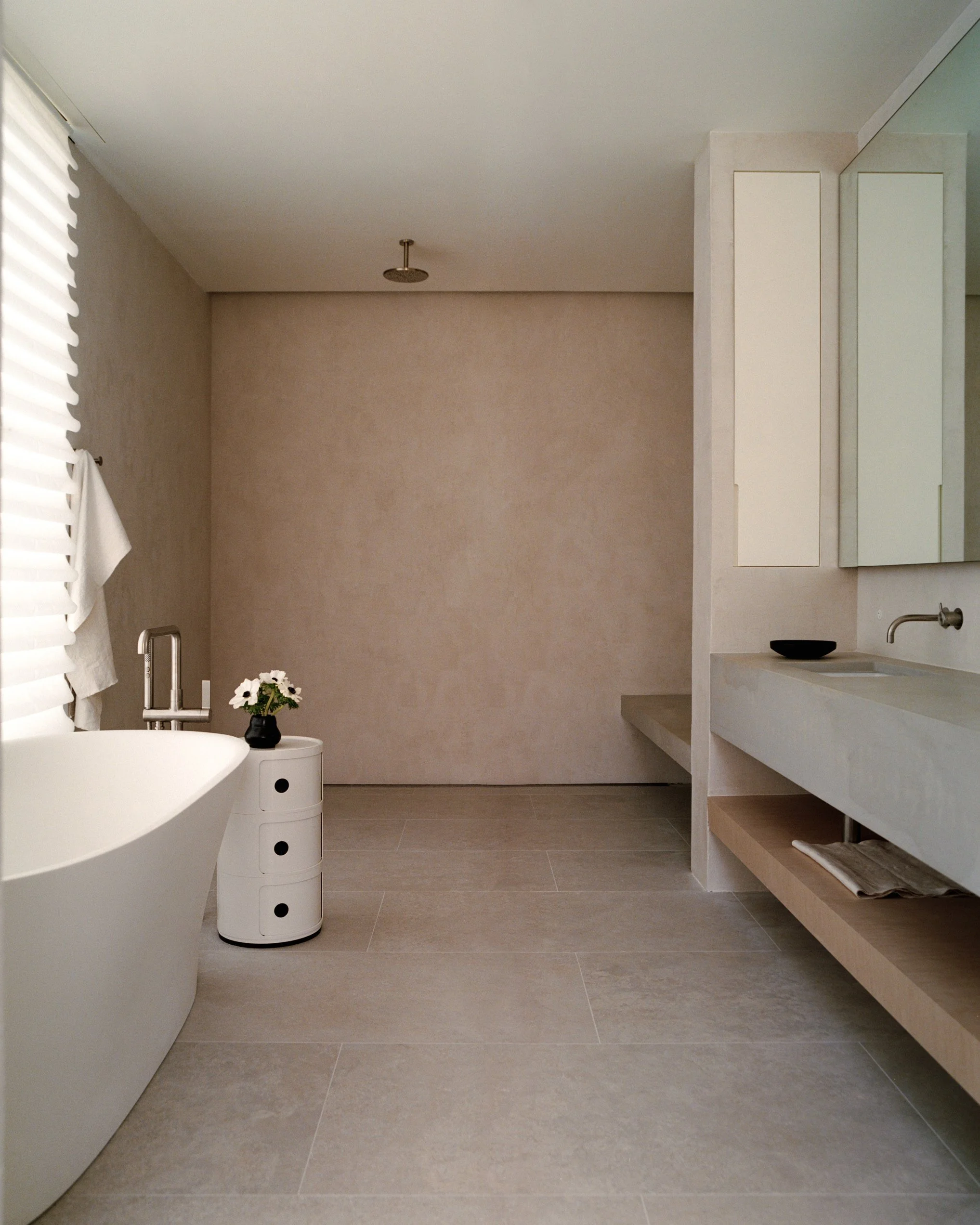 Bathroom with a freestanding tub and a floating stone vanity with a black vessel sink at a Ghent, NY home by JG Neukomm Architecture