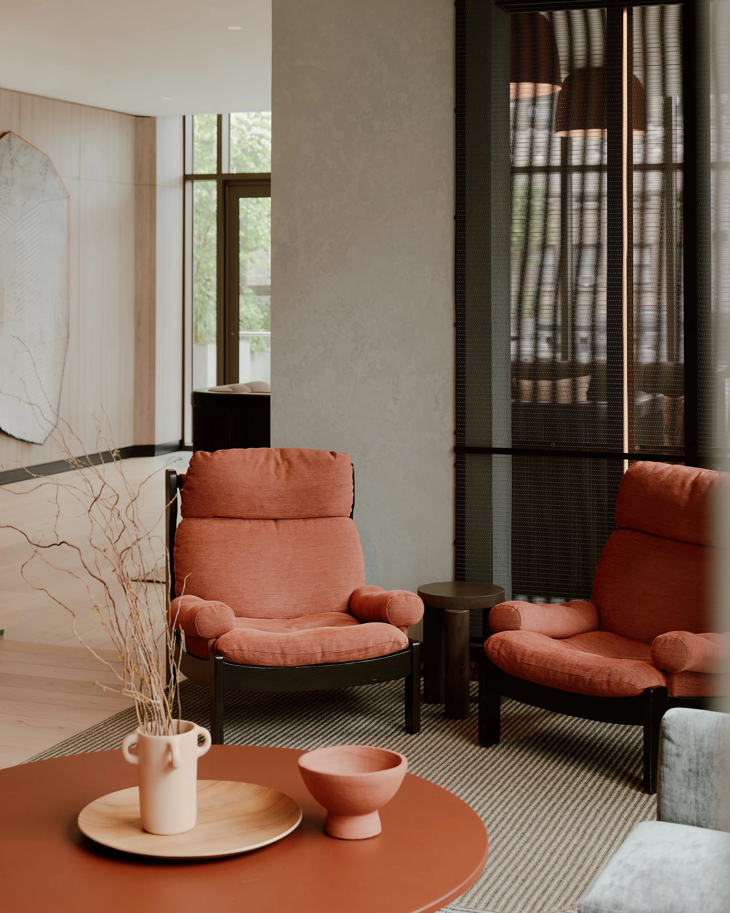 Lounge seating with rust upholstered chairs and terracotta tables at The Suffolk, a Lower East Side residential building, interiors by JG Neukomm Architecture