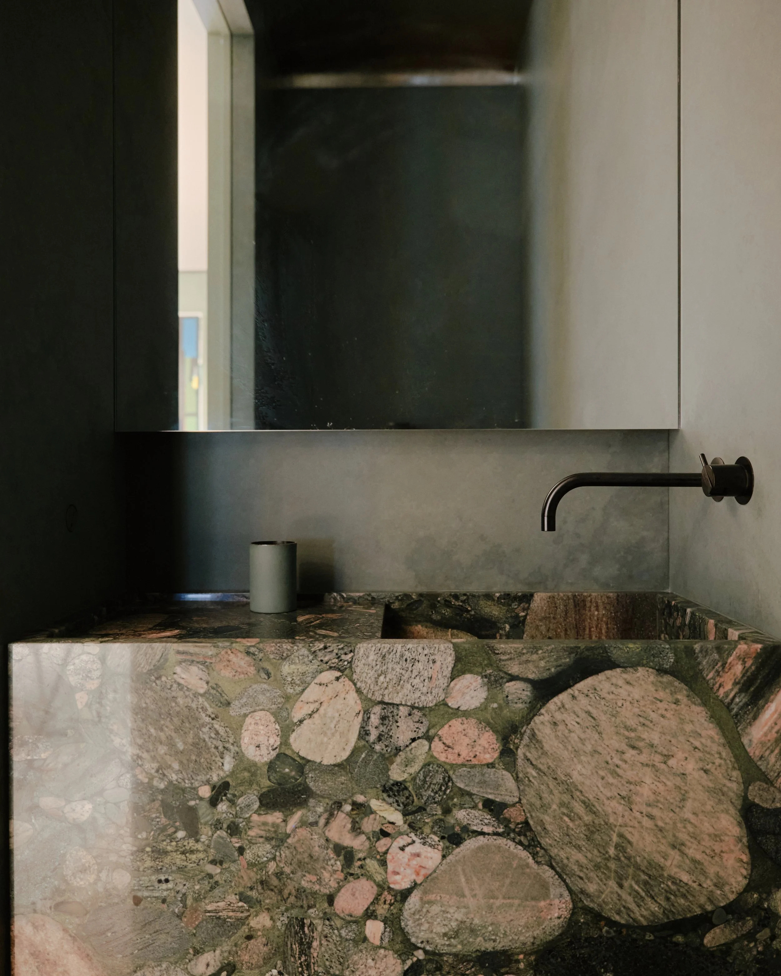 Powder room with a conglomerate-stone sink and dark wall in a West Village townhouse by JG Neukomm Architecture