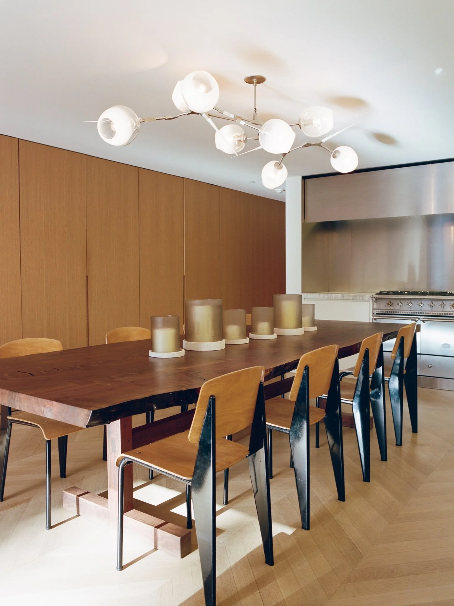 Open-plan dining area with sculptural globe chandelier and warm wood paneling in Fabien Baron's West Village townhouse by JG Neukomm Architecture