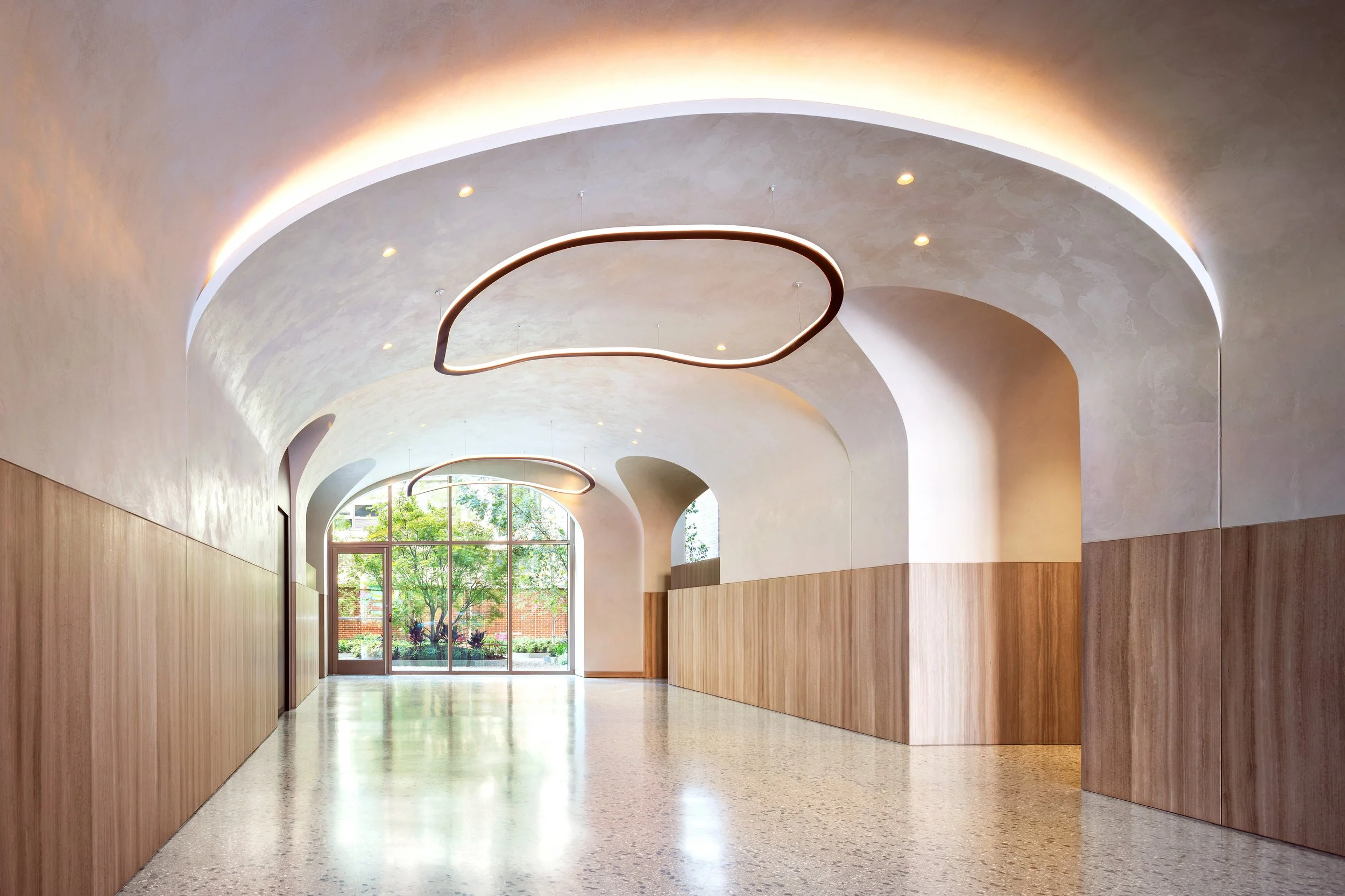 Entry way with a sculptural arched plaster ceiling and illuminated ring pendants at The Suffolk, a Lower East Side residential building, interiors by JG Neukomm Architecture