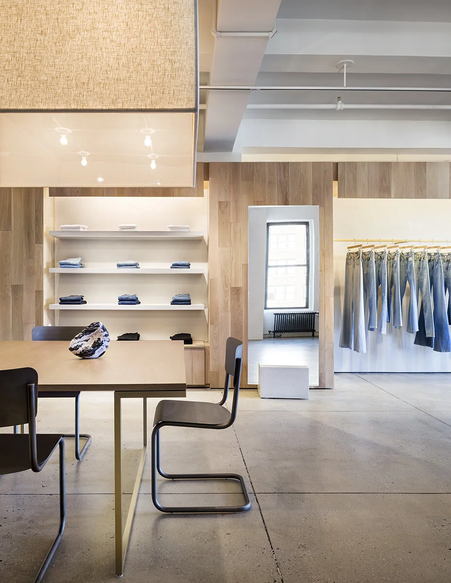 FRAME Denim showroom detail with white shelving, folded garments, and a denim rail against oak paneling