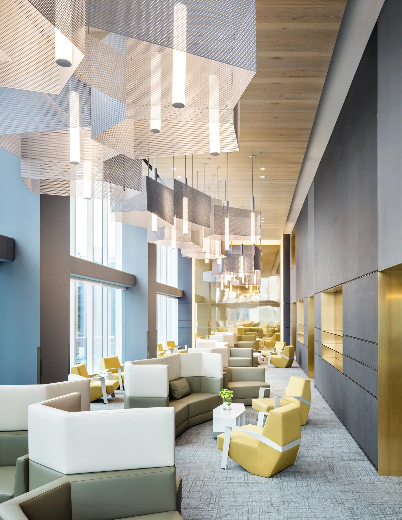 GNA residential lounge with curved yellow and white seating, a suspended mesh ceiling canopy, and tall windows