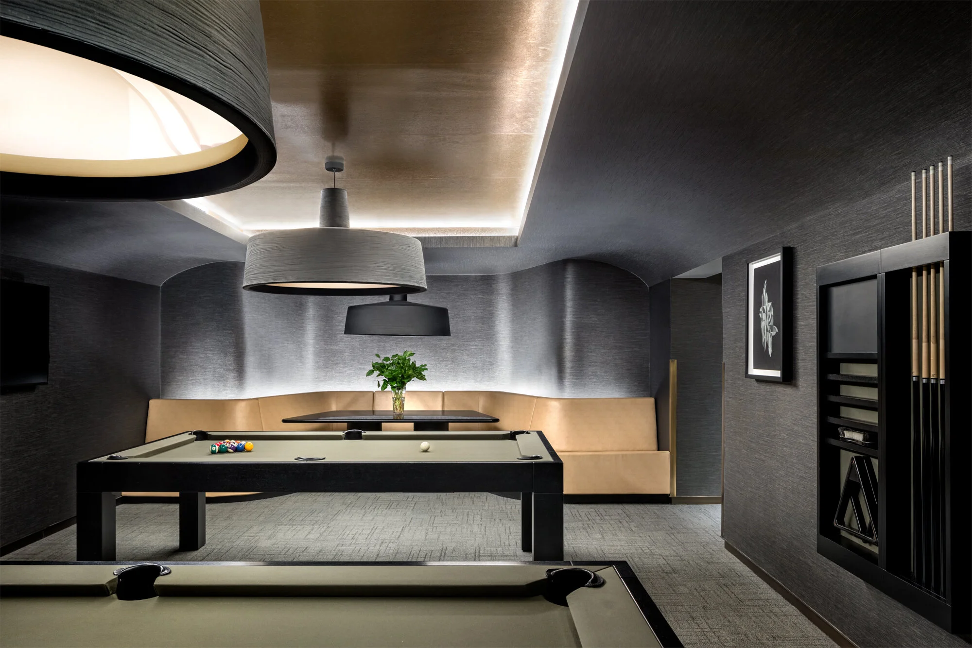 JGNA residential billiards room with two pool tables, a curved leather banquette, and textured grey walls