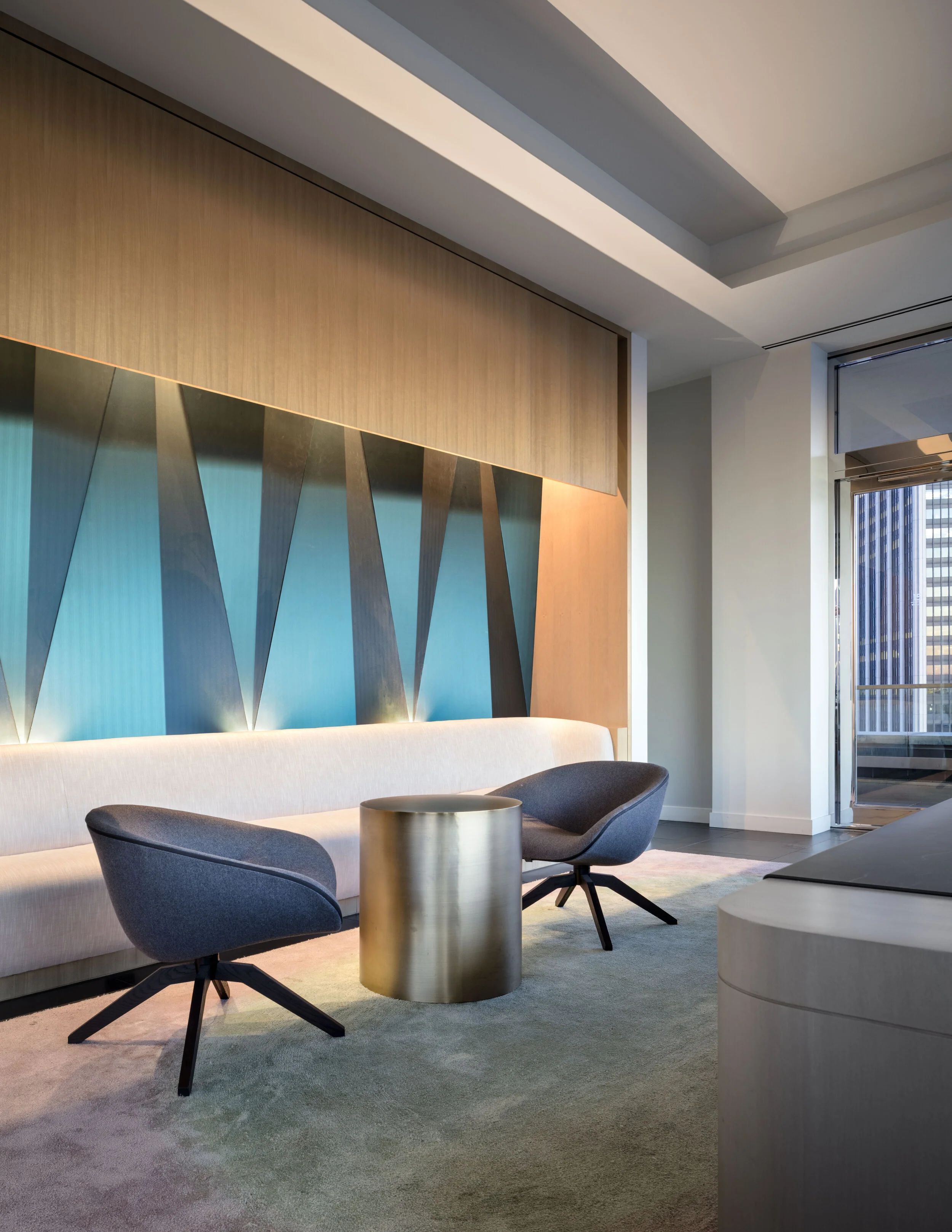 JGNA residential lounge with a backlit geometric feature wall, paired swivel chairs, and a metal side table