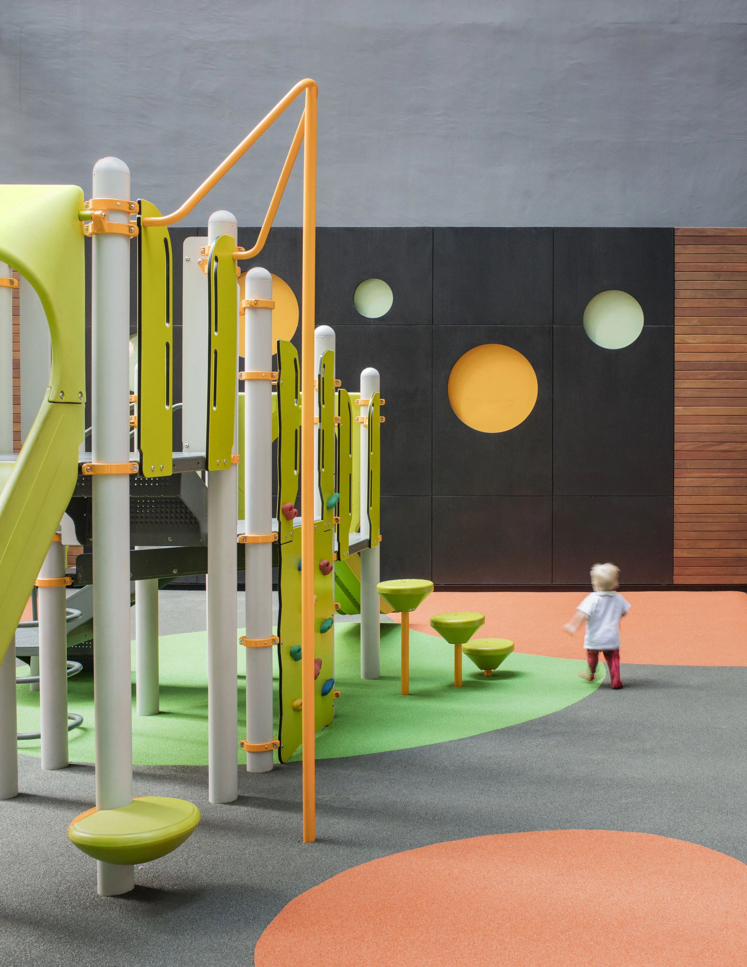 JGNA residential rooftop children's playground with colorful climbing equipment and a play surface