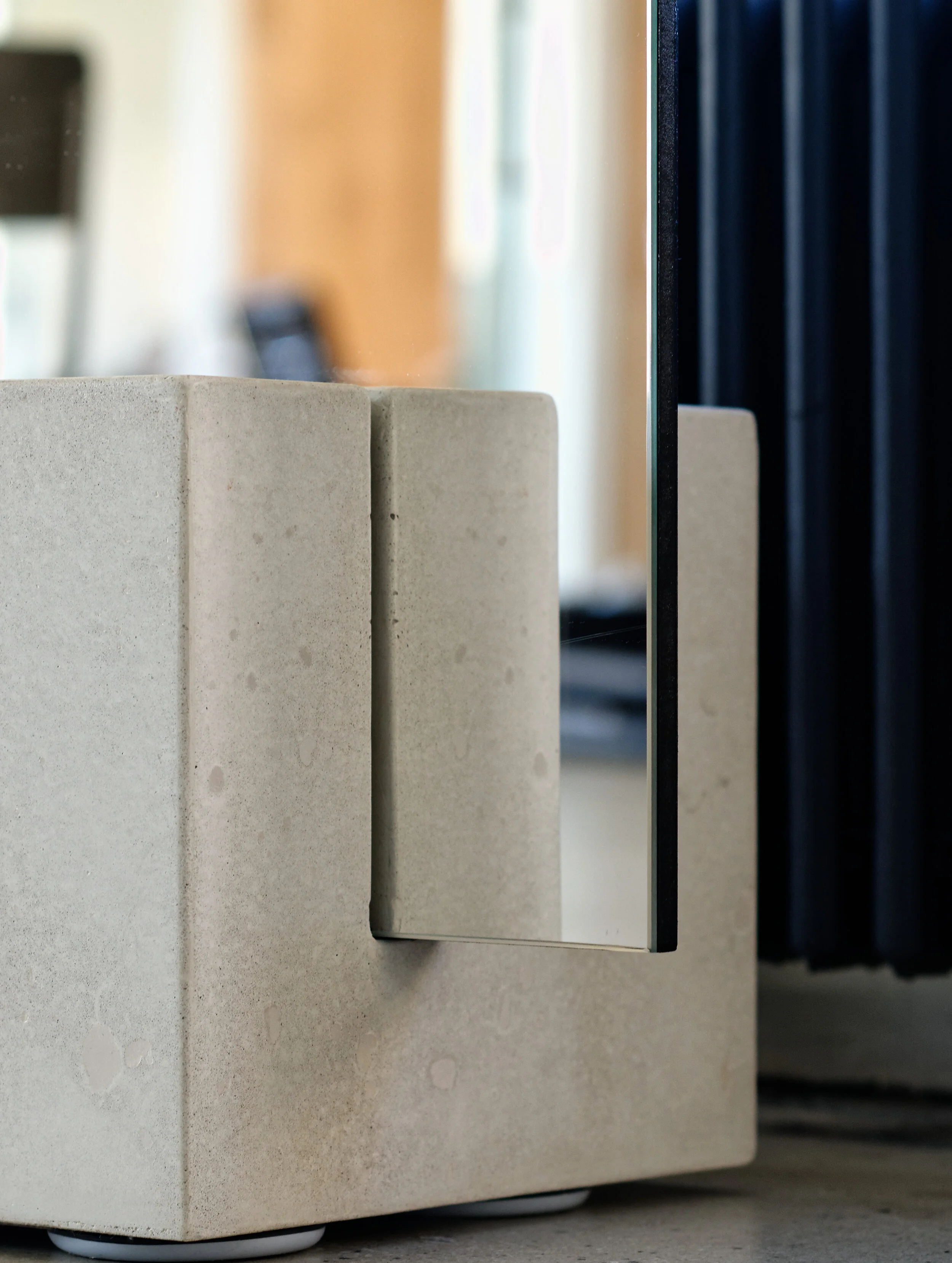 FRAME Denim showroom detail of a cast concrete plinth meeting a mirrored surface