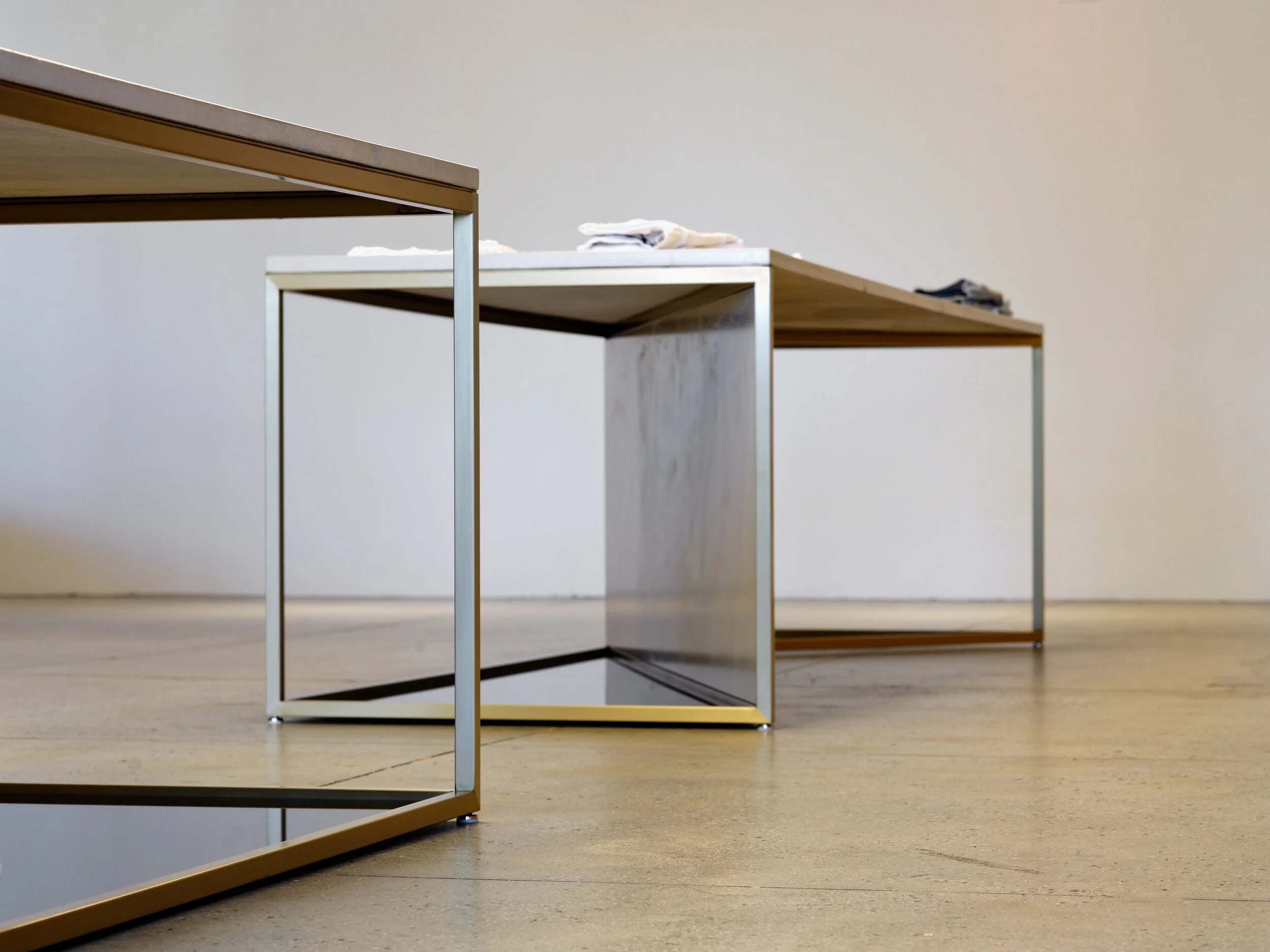 FRAME Denim showroom detail of a brass and mirrored display table base on concrete flooring
