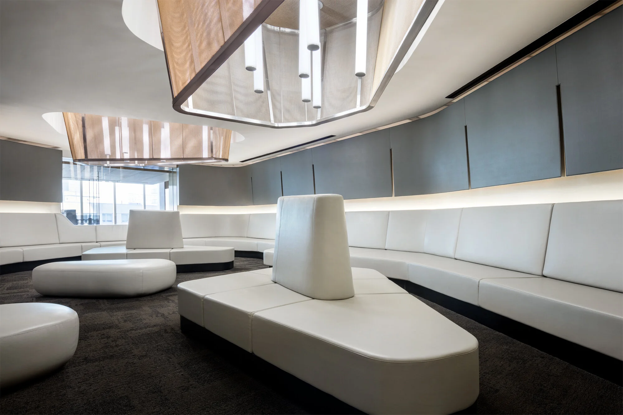 JGNA residential lounge with a curved white leather banquette below a sculptural mesh and oak ceiling canopy