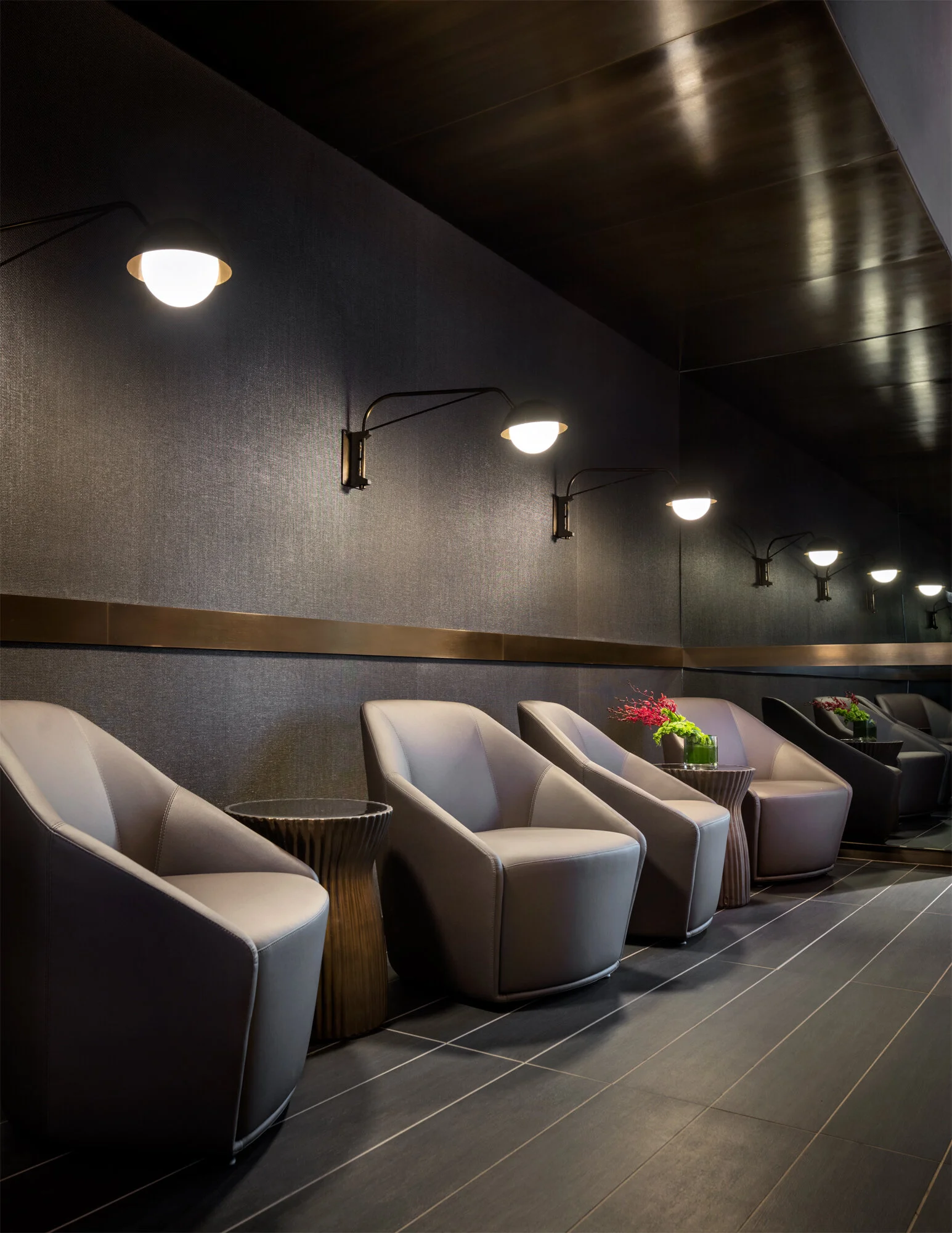 JGNA residential screening lounge with rows of grey armchairs and a line of swing-arm wall sconces