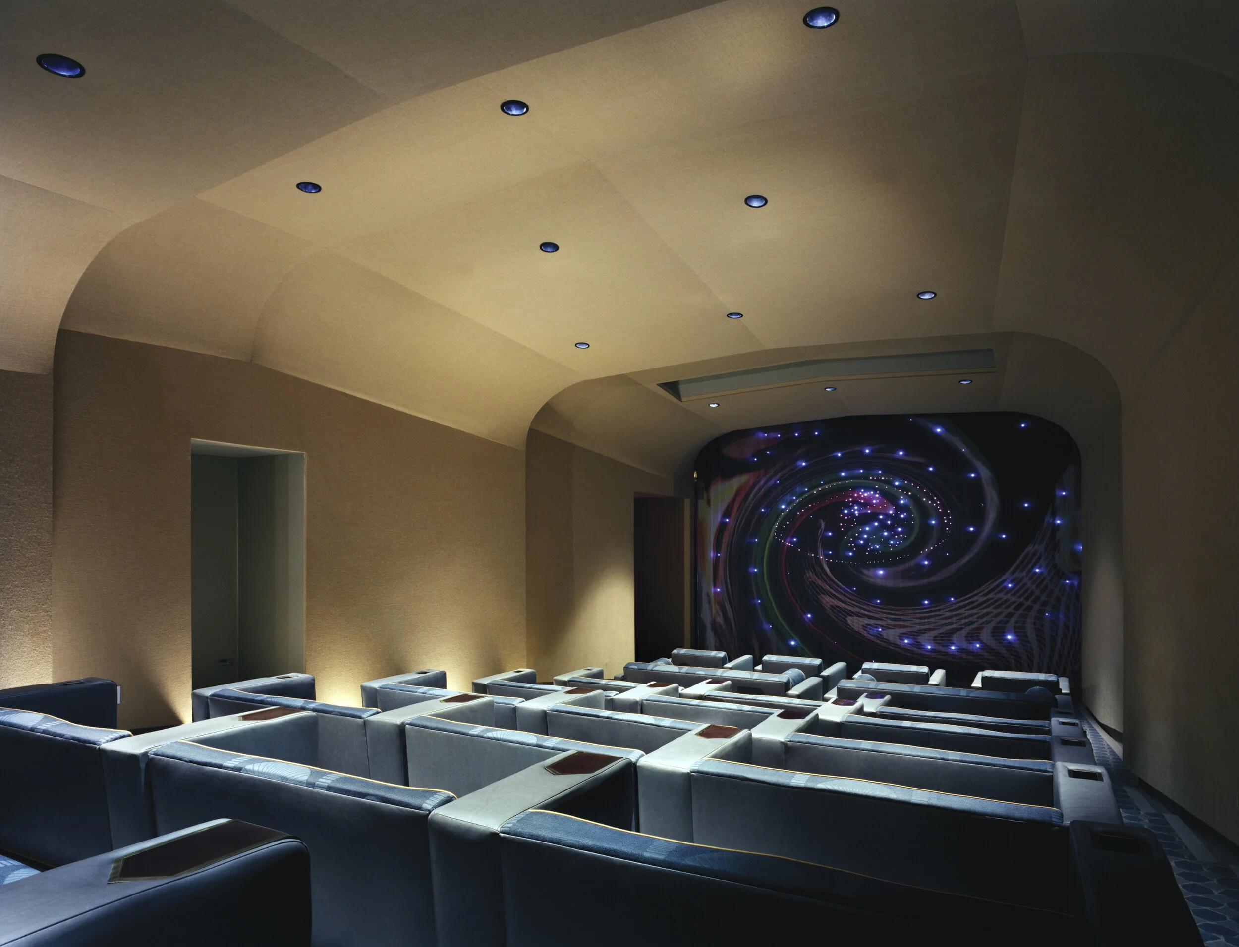 JGNA screening room with a vaulted plaster ceiling, blue lounge seating, and a backlit galaxy mural