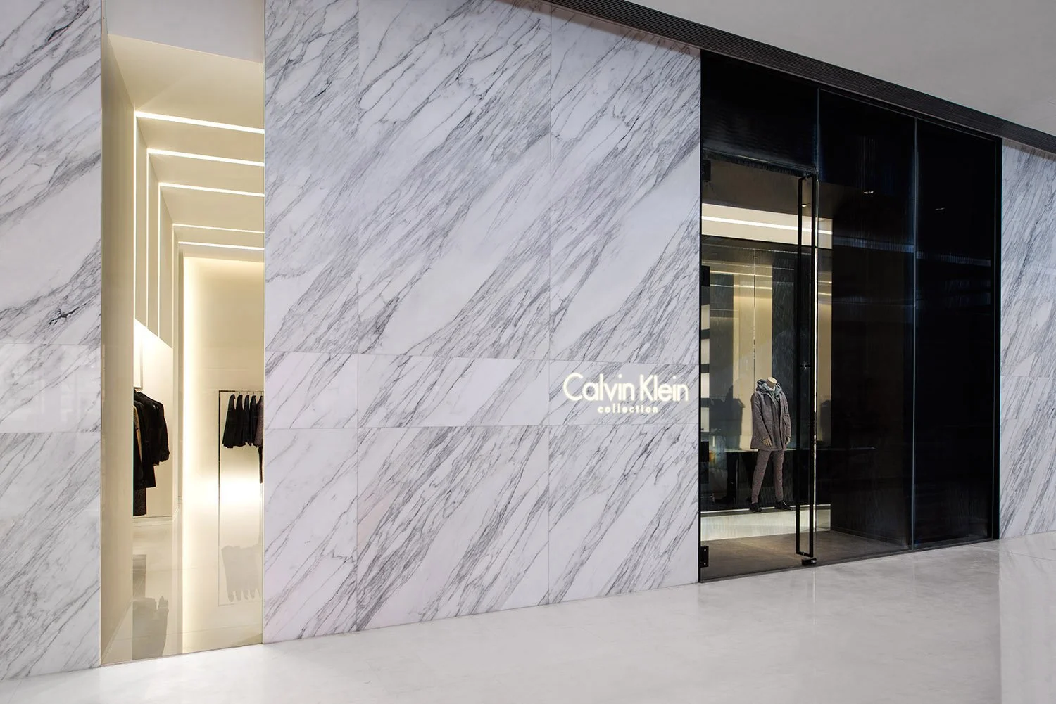 Calvin Klein Collection storefront with a veined marble facade, brand signage, and glass entry, designed by JGNA