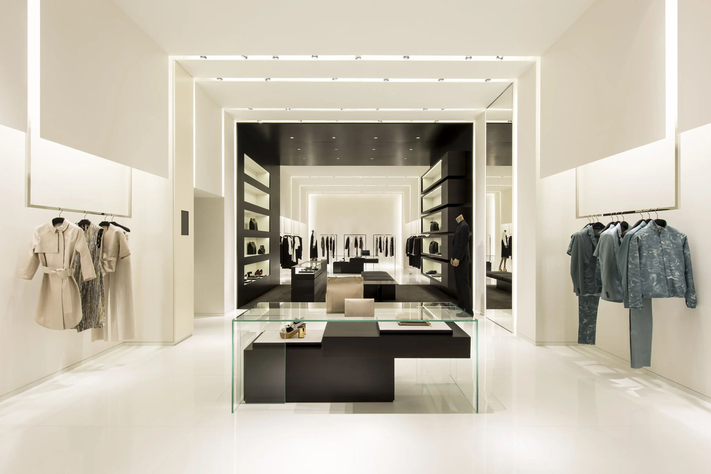 Calvin Klein Collection store interior with nested lit portals framing a glass display table and menswear rails